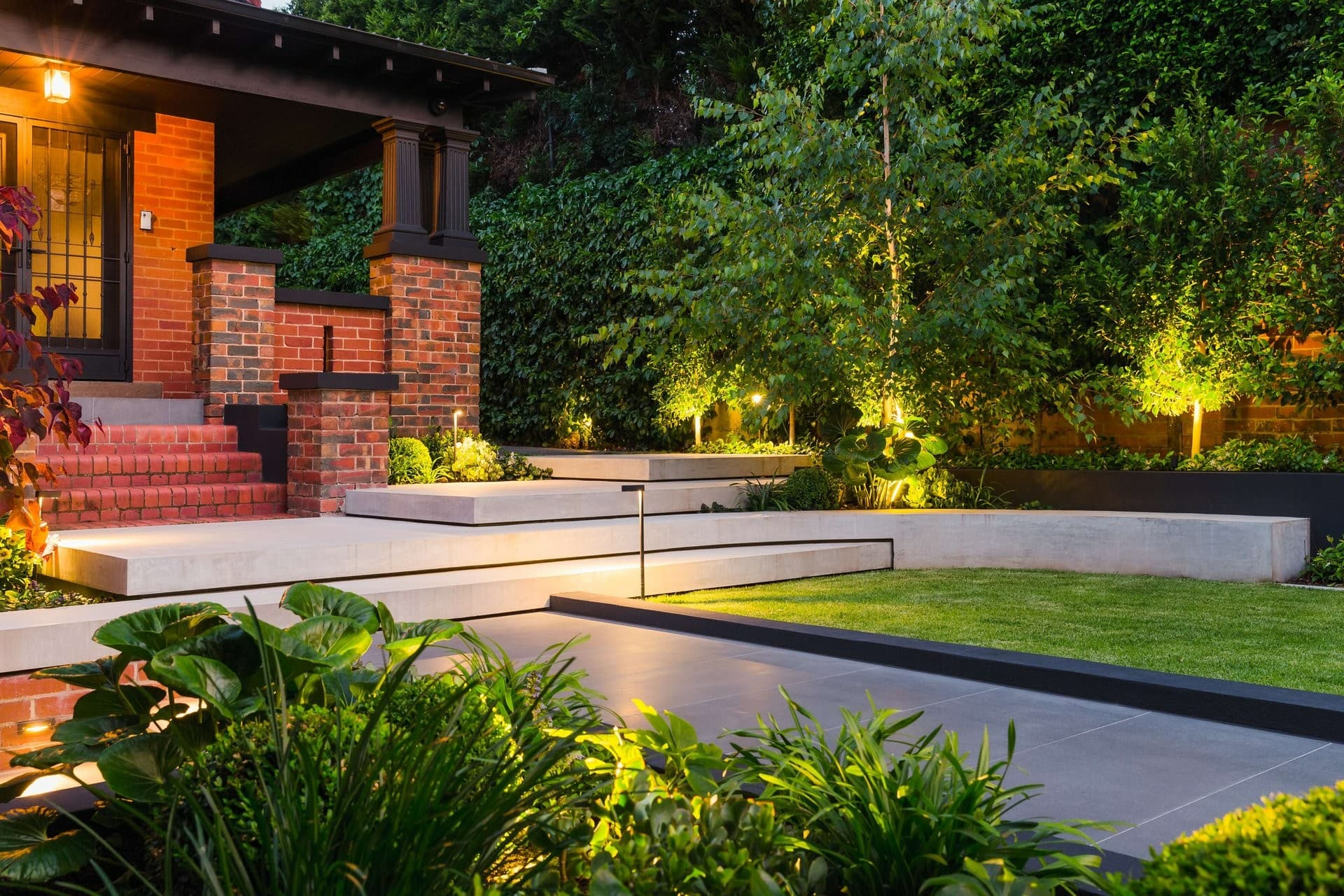 Designed Adelaide garden at dusk with terraced planting and warm lighting